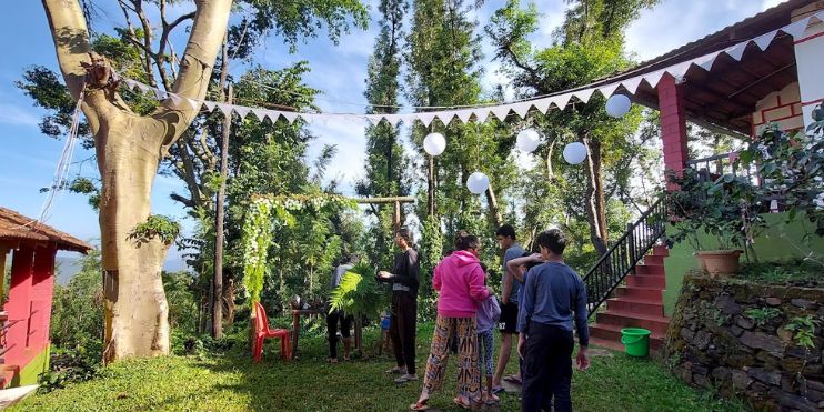 People standing around a tree in a yard at Ranga Taana Resort, Chikmagalur, offering adventure activities and guided nature walks.