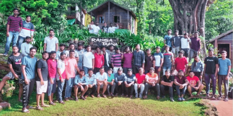 A group of people smiling for a photo in front of a house. Experience Ranga Taana: Your Ideal Hirekolale Lake Homestay.