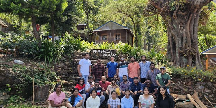 A group of people posing for a photo in front of a tree at Ranga Taana Resort Chikmagalur.