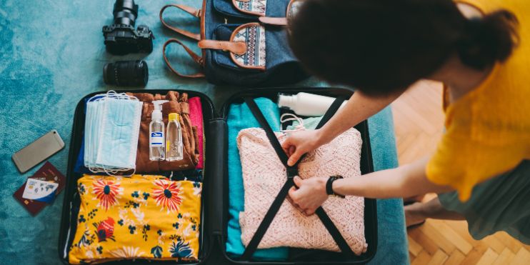 A woman carefully packing her luggage into a suitcase.