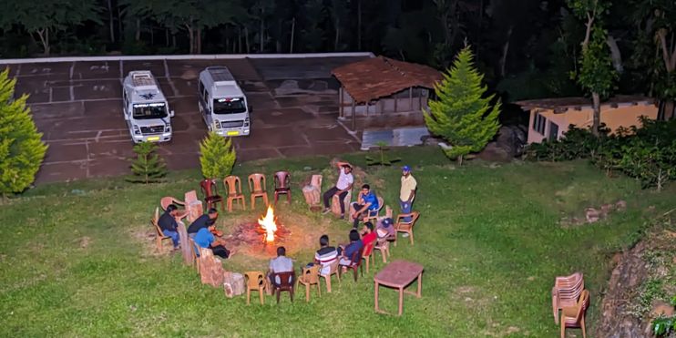 A group of people sitting around a fire pit at Ranga Taana Resort, enjoying relaxation and wellness activities.