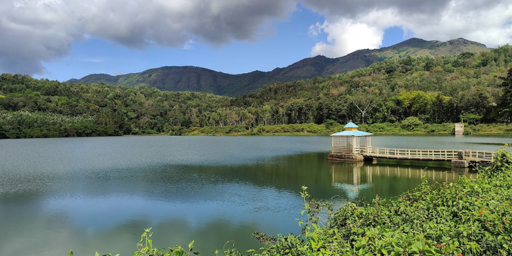 Scenic view of Hirekolale Lake with dock and mountains in the background.