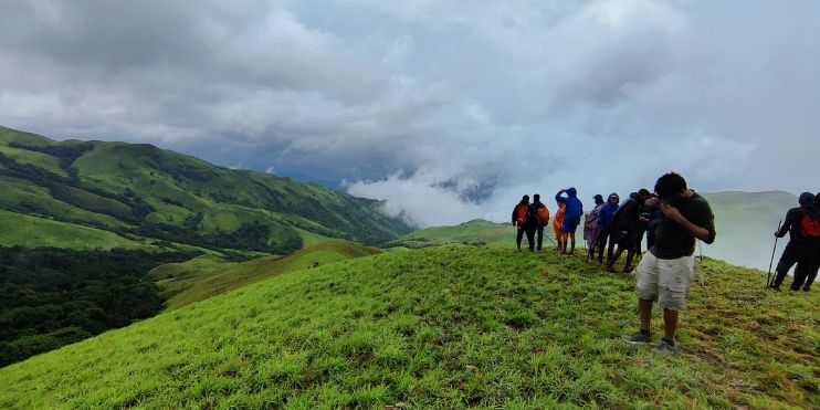 Several individuals standing on a grassy hill, enjoying the scenic view.