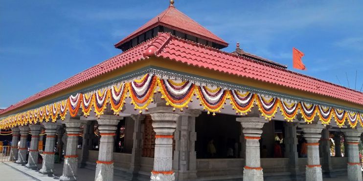 A vibrant temple adorned with orange and yellow decorations on the roof, symbolizing devotion and cultural heritage.