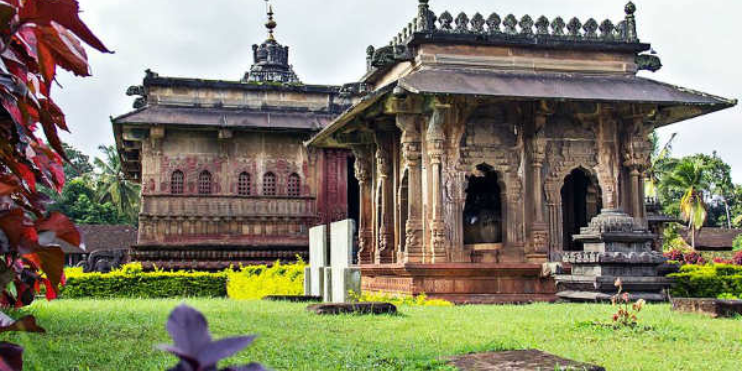 A serene temple in Keladi and Ikkeri, encircled by vibrant, lush green grass, showcasing nature's beauty and tranquility.