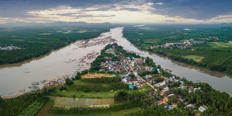 Aerial view of Shivamogga showcasing a winding river flowing through the town, surrounded by lush greenery and urban structures.