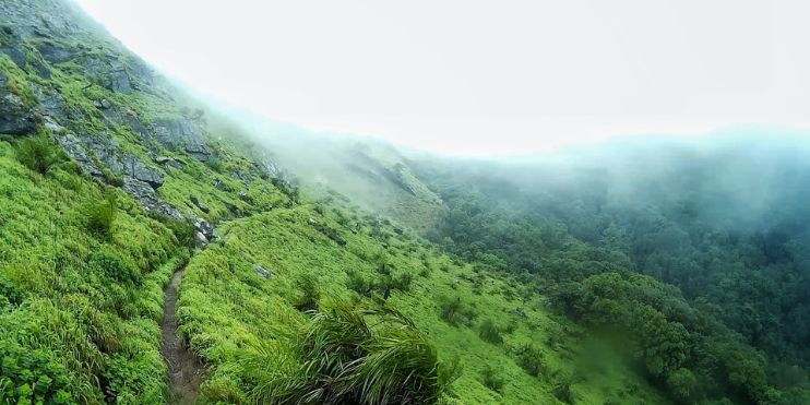 Scenic view of a mountain trail, ideal for winter trekking in Chikmagalur, showcasing clear skies and calm temperatures.