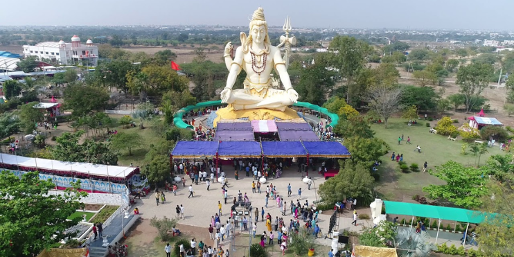 A large statue of a Hindu god stands majestically in a park, symbolizing spirituality and cultural heritage during festivals.