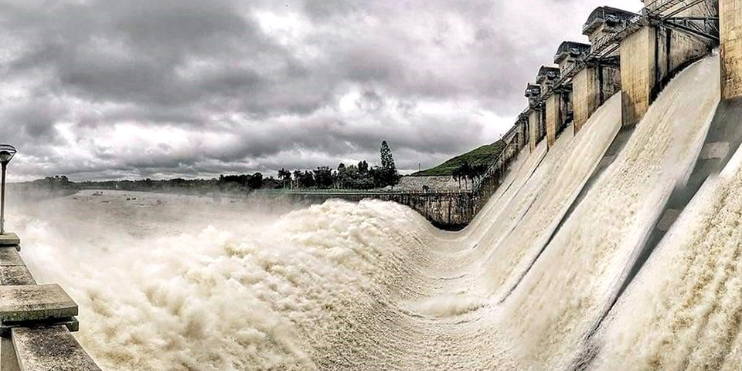 A large dam with water cascading over it, surrounded by scenic views and nearby attractions like Gorur Dam and Hasanamba Temple.