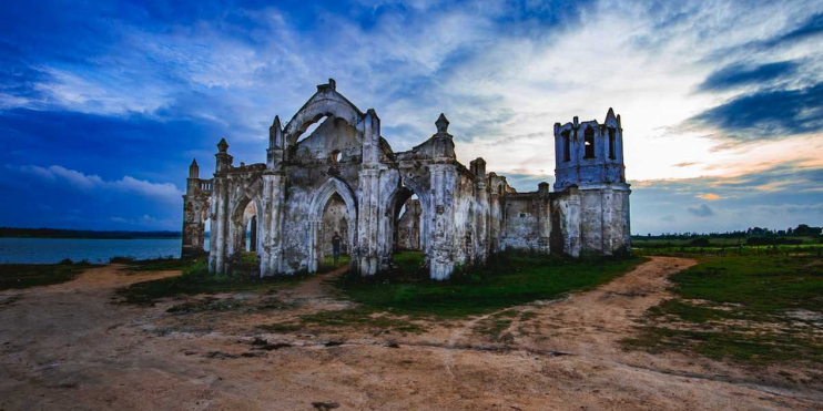 The ruins of an old church stand isolated, surrounded by nature, showcasing a blend of history and serene landscapes.