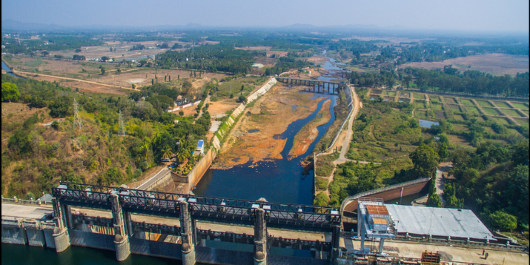 Aerial view of Bhadra Dam, showcasing water flow amidst lush hills and forests near Shimoga, a gateway to scenic attractions.