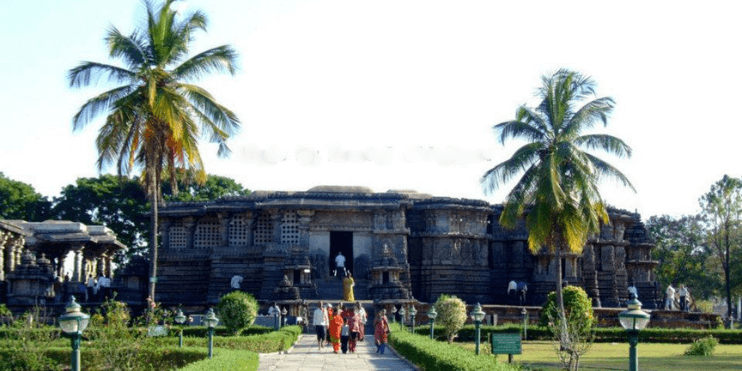 A temple nestled among vibrant green trees, showcasing the beauty of Halebeedu's historical architecture.