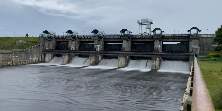 A large dam with water cascading over it, surrounded by lush greenery, showcasing the beauty of nature and engineering.