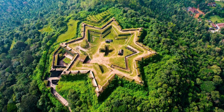 Aerial view of Manjarabad Fort, a star-shaped structure surrounded by lush green forest, offering stunning Western Ghats vistas.