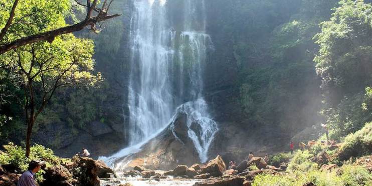 A serene waterfall cascades amidst lush trees and rugged rocks, perfect for a Christmas adventure getaway.