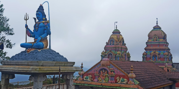 A statue of Lord Shiva atop a building, symbolizing divine presence and traditional Indian architectural beauty.