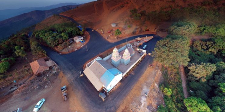 Aerial view of a church perched on a hillside, surrounded by lush greenery and scenic landscapes.