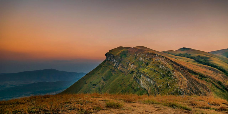 A majestic mountain silhouette against a vibrant sunset, creating a romantic atmosphere for couples in Kemmangundi.