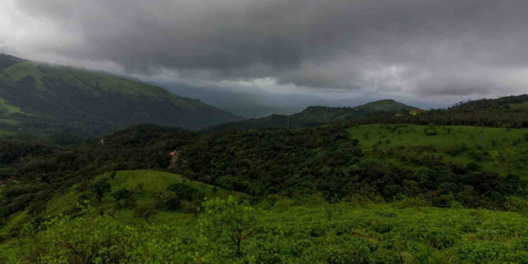 A scenic view of mountains and green hills beneath a cloudy sky, showcasing the beauty of nature during the Baba Budangiri Trek.