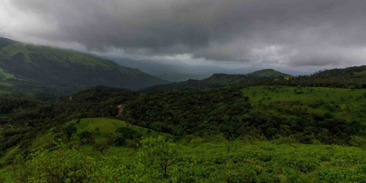 A panoramic view of mountains and green hills beneath a cloudy sky, showcasing the beauty of nature's landscape.