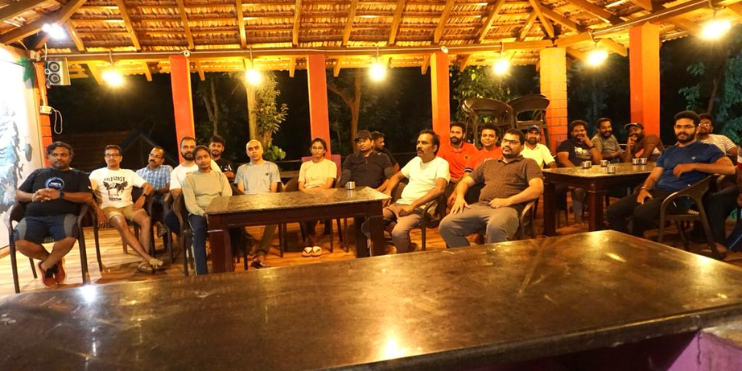 A group of individuals gathered at tables inside a rustic wooden hut, enjoying their time together.