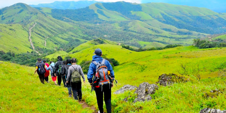 A group of hikers ascending Mullayanagiri, Karnataka's highest peak, enjoying stunning views and a sunrise at the summit.