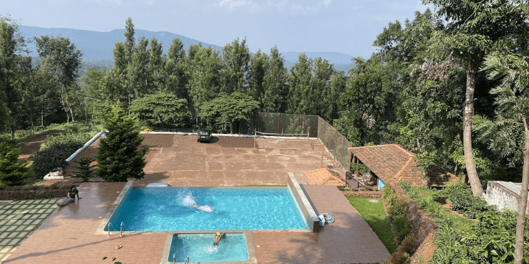 A serene swimming pool surrounded by lush greenery, ideal for relaxation and leisure at Chikmagalur resorts.
