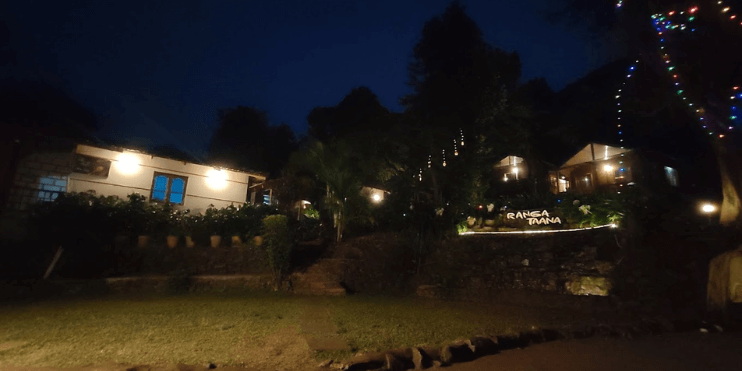 A beautifully lit house at night, surrounded by glowing lights on the lawn, creating a warm and inviting atmosphere.