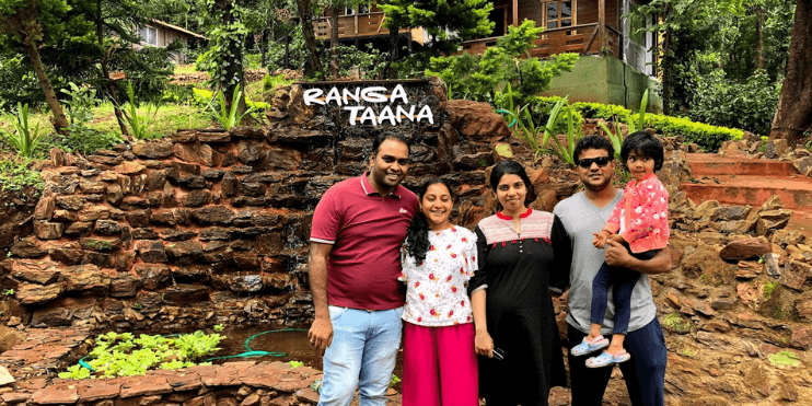 A family smiles for a photo in front of a cascading waterfall, capturing a moment of joy in a serene natural setting.