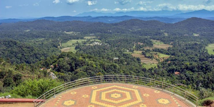 Mountain view overlooking a lush valley in Coorg, showcasing misty landscapes and coffee plantations.