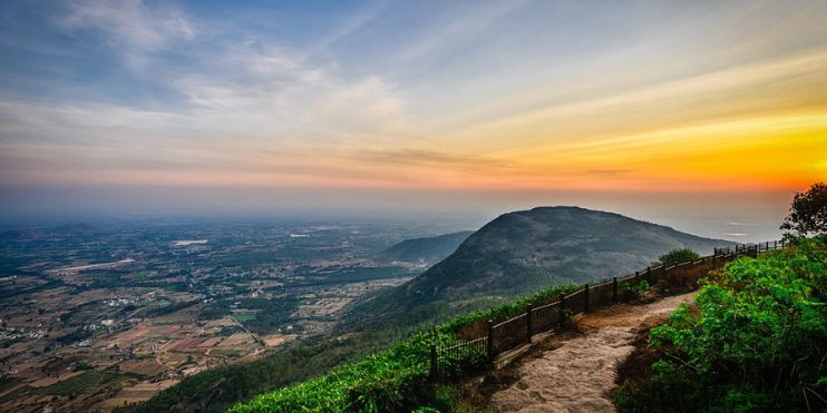 Sunset over Kodaikanal, Kerala, India, showcasing vibrant orange and pink hues in the sky above tranquil hills.