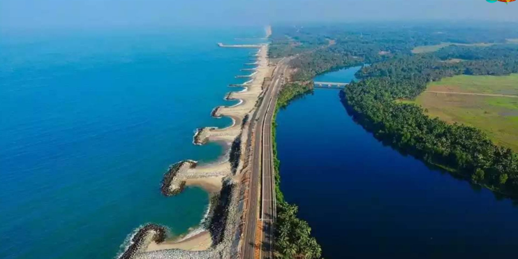 A scenic coastal road with a bridge, flanked by the Arabian Sea on one side and the Suparnika River on the other.