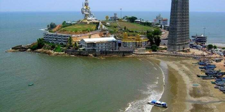 A large tower topped with a statue of Lord Shiva, overlooking Murudeshwar Beach's scenic coastline and vibrant atmosphere.