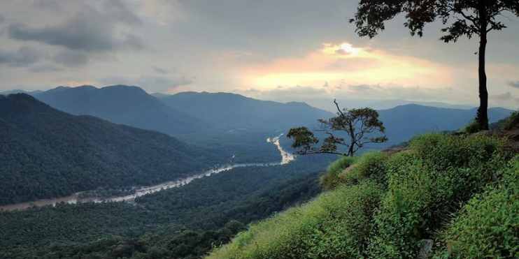 Sunset over mountains and river, casting golden hues across the landscape, perfect for a serene trek at Jenukallu Gudda.