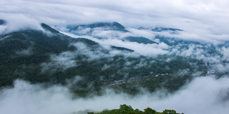 A panoramic view of mountains and clouds from a high vantage point, showcasing the beauty of the Western Ghats.