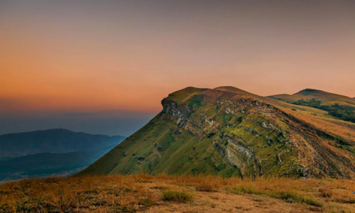 A majestic mountain silhouette against a vibrant sunset, creating a romantic atmosphere for couples in Kemmangundi.
