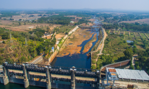 Aerial view of Bhadra Dam, showcasing water flow amidst lush hills and forests near Shimoga, a gateway to scenic attractions.